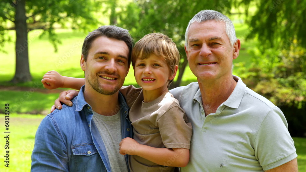 Three generations of men smiling at camera in the park Three generations of men smiling at camera in the park
