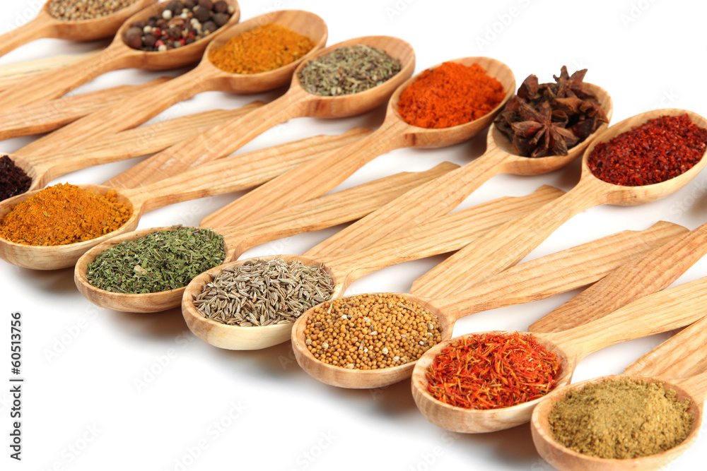 Assortment of spices in wooden spoons, isolated on white