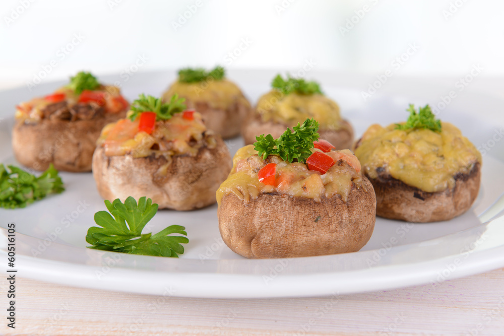 Stuffed mushrooms on plate on table on light background Stuffed mushrooms on plate on table on light background