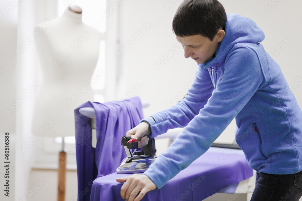 Tailor ironing in her shop Tailor ironing in her shop