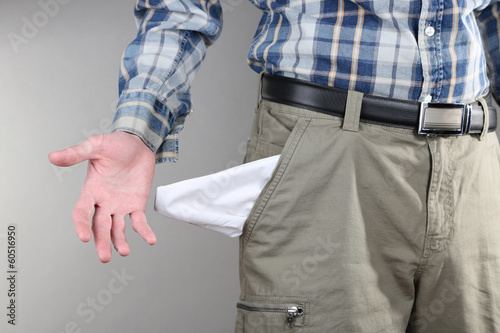 Man showing his empty pocket on grey background