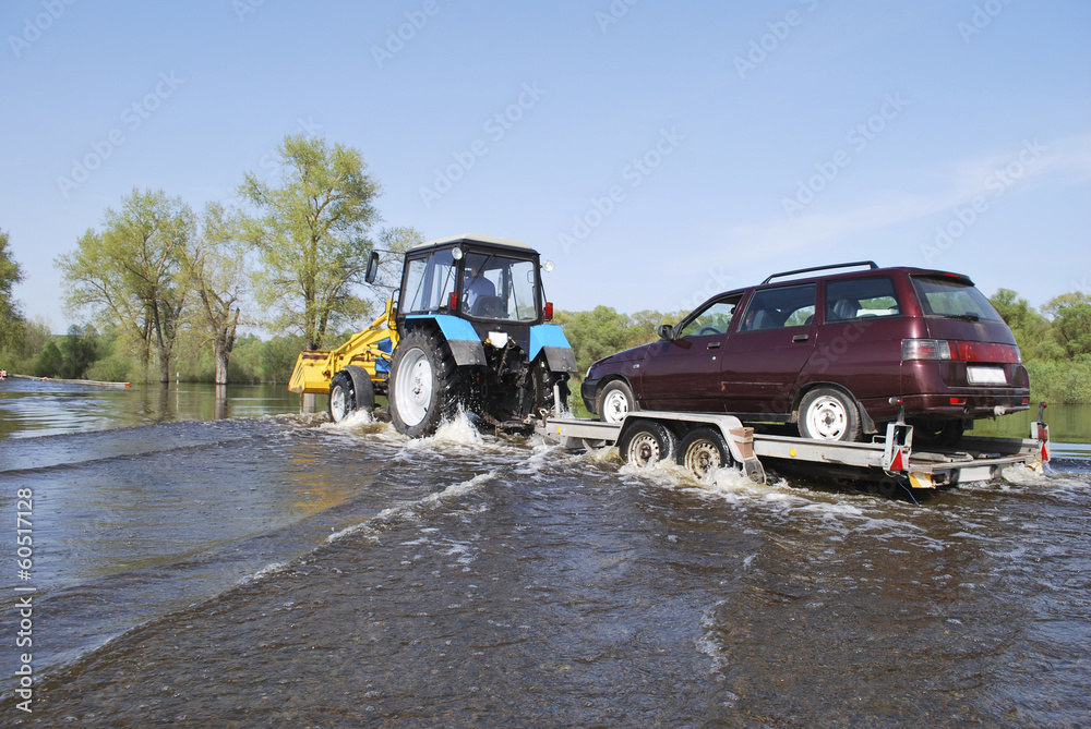 Floods, it flooded road tractor carries cars.