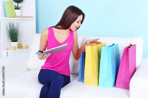 Beautiful young woman holding tablet with shopping bags