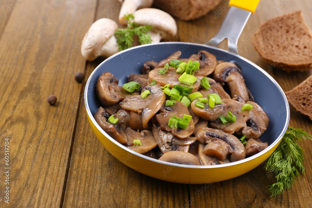Delicious fried mushrooms in pan on table close-up Delicious fried mushrooms in pan on table close-up