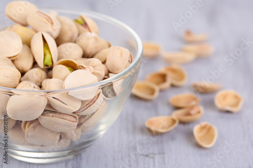 Pistachio nuts in glass bowl on wooden background