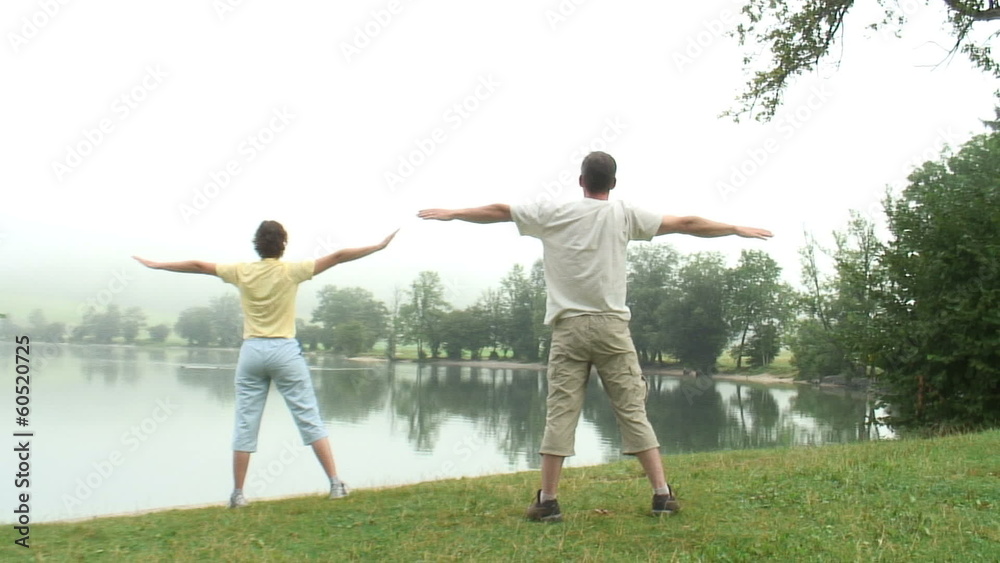 Paar macht Gymnastik  am See mit Nebel