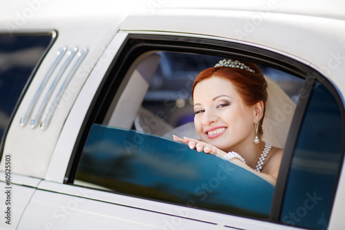 Happy lovely red hair young bride in limo.