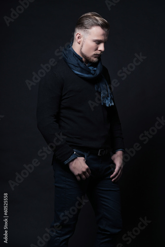 Man winter fashion. Wearing black sweater and scarf. Blonde hair