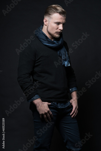 Man winter fashion. Wearing black sweater and scarf. Blonde hair