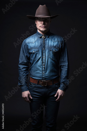 Modern fashion cowboy. Wearing brown hat and blue jeans shirt. B