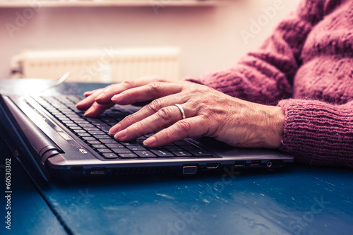 Old woman working on laptop computer at home photo