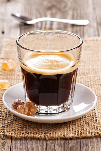 Black coffee in a glass with crystal sugar