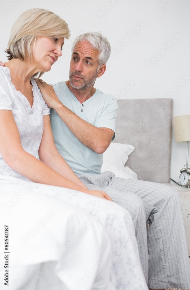 Man consoling tensed woman in bed Man consoling tensed woman in bed