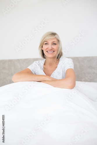 Pretty smiling mature woman sitting on bed