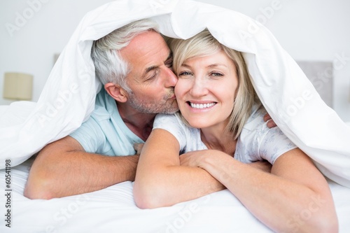 Closeup of mature man kissing womans cheek in bed