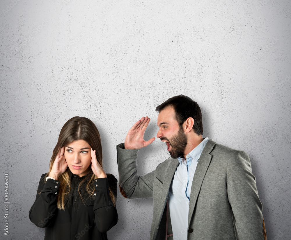 Businessman screaming at his girlfriend over grey background Businessman screaming at his girlfriend over grey background