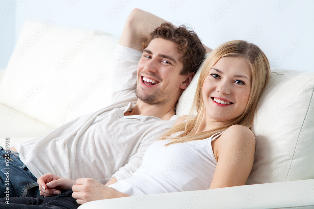 Fototapeta premium Young beautiful couple on a sofa at home
