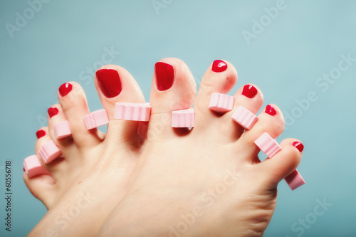 foot pedicure applying red toenails on blue