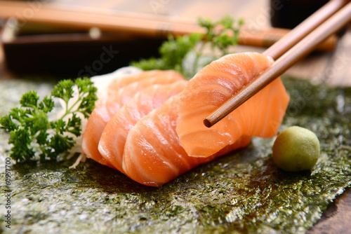 Chopsticks holding a salmon sashimi slice