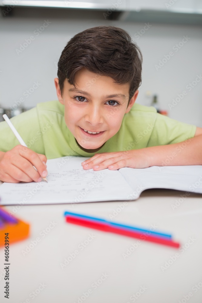 Smiling boy doing homework in kitchen