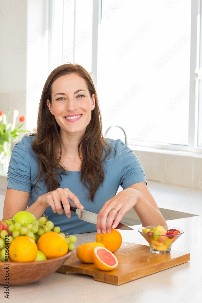 Portrait of a woman cutting fruits in kitchen