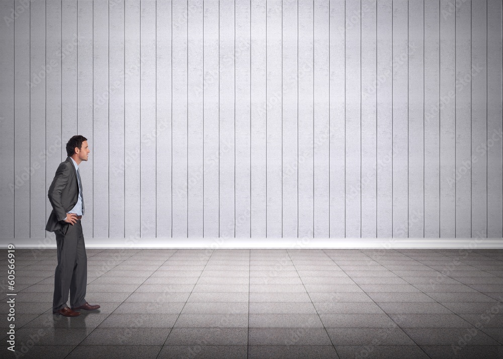 Fototapeta premium Composite image of smiling businessman with hands on hips