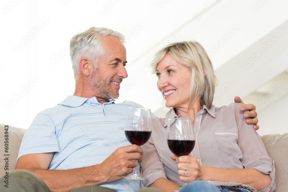 Smiling mature couple with wine glasses sitting on sofa Smiling mature couple with wine glasses sitting on sofa