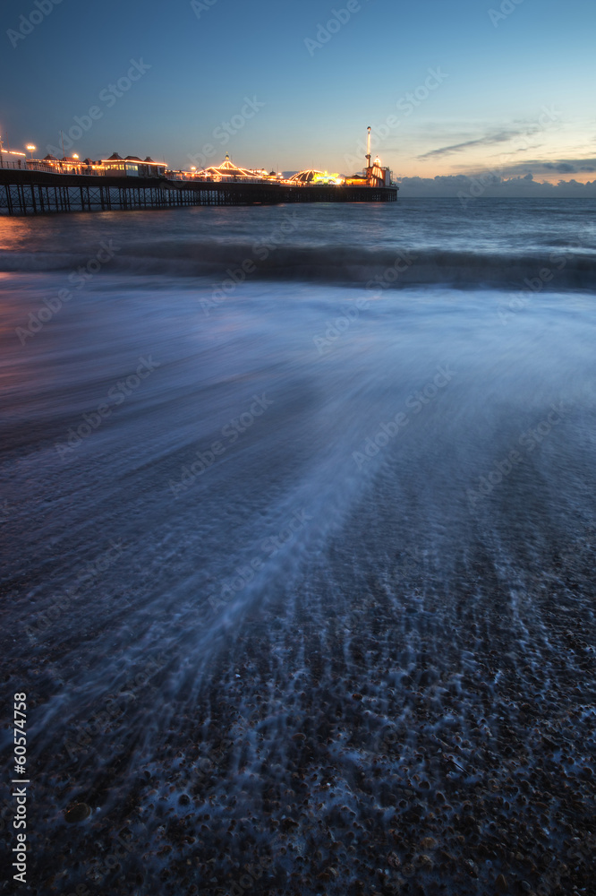 Beautiful long exposure landscape of waves receding with pier in