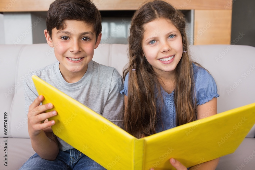 Portrait of smiling siblings with photo album in living room Portrait of smiling siblings with photo album in living room