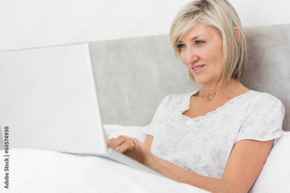 Mature woman using laptop in bed Mature woman using laptop in bed