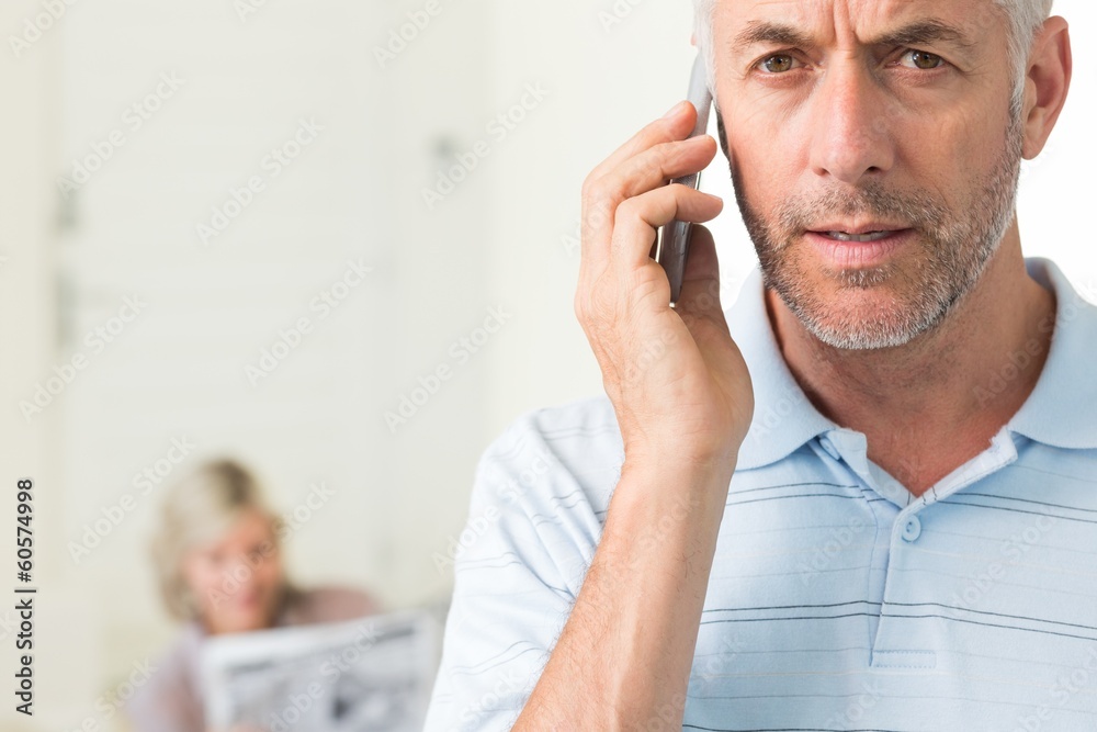 Mature man using cellphone with woman reading newspaper Mature man using cellphone with woman reading newspaper