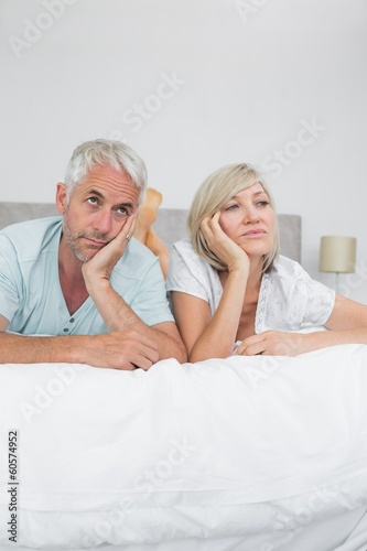 Displeased mature man and woman lying in bed © WavebreakMediaMicro
