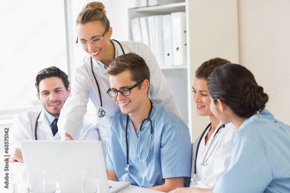 Smiling doctors and nurses discussing over laptop Smiling doctors and nurses discussing over laptop