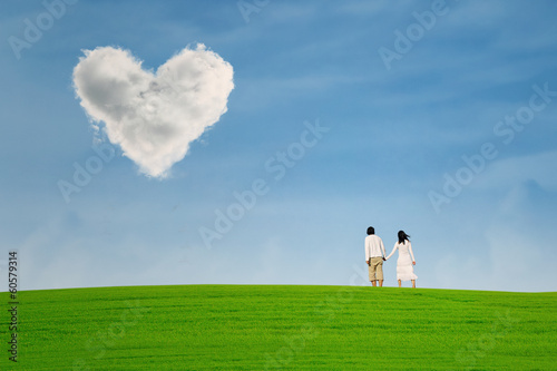 Couple at green hill under heart shape cloud