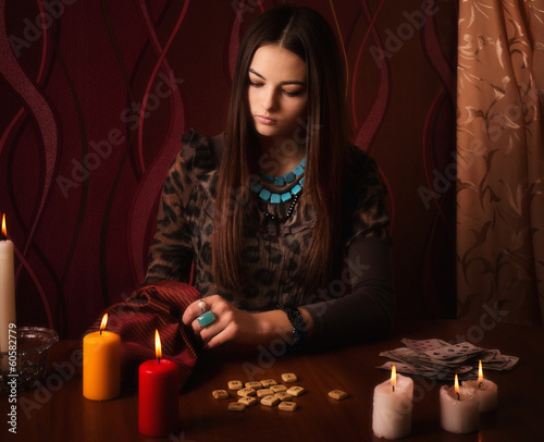 Young woman with runes and divination cards in room