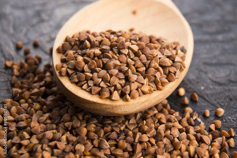 Buckwheat seeds on wooden spoon in closeup Buckwheat seeds on wooden spoon in closeup