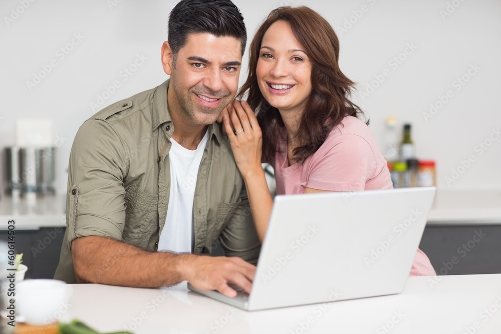 Portrait of a happy couple using laptop in kitchen Portrait of a happy couple using laptop in kitchen