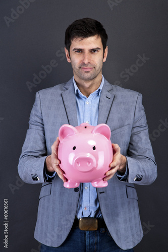 Businessman with piggy bank over dark background