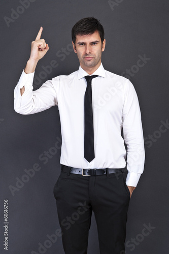 Young businessman criticizing on gray background