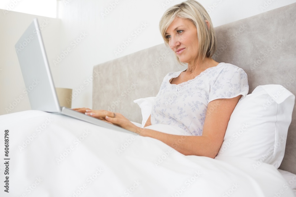 Woman using laptop in bed at home Woman using laptop in bed at home