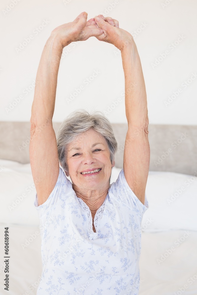 Smiling senior woman stretching on bed Smiling senior woman stretching on bed