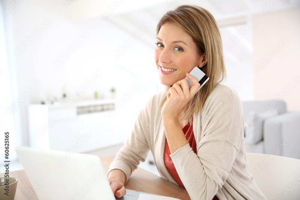 Cheerful middle-aged woman buying on internet Cheerful middle-aged woman buying on internet