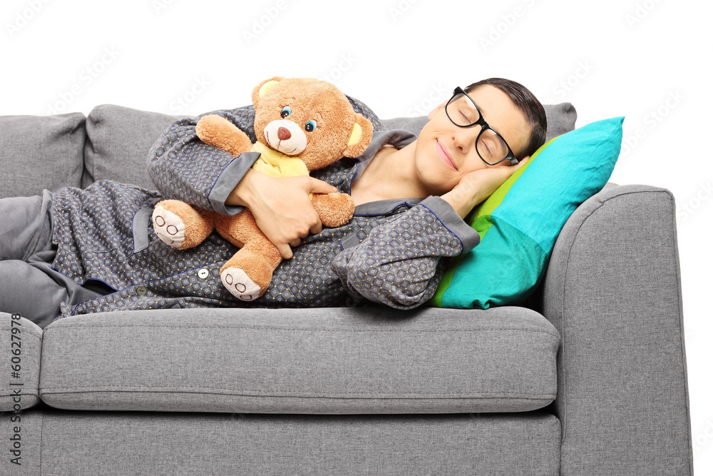 Young guy sleeping on sofa holding a teddy bear Young guy sleeping on sofa holding a teddy bear