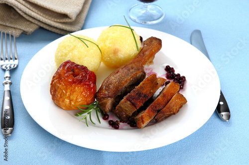 Duck leg with potato dumplings, red apple and cranberries photo