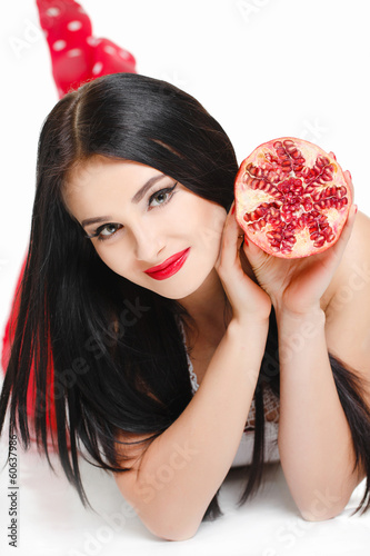 Beautiful brunette girl in studio with garnet fruit photo