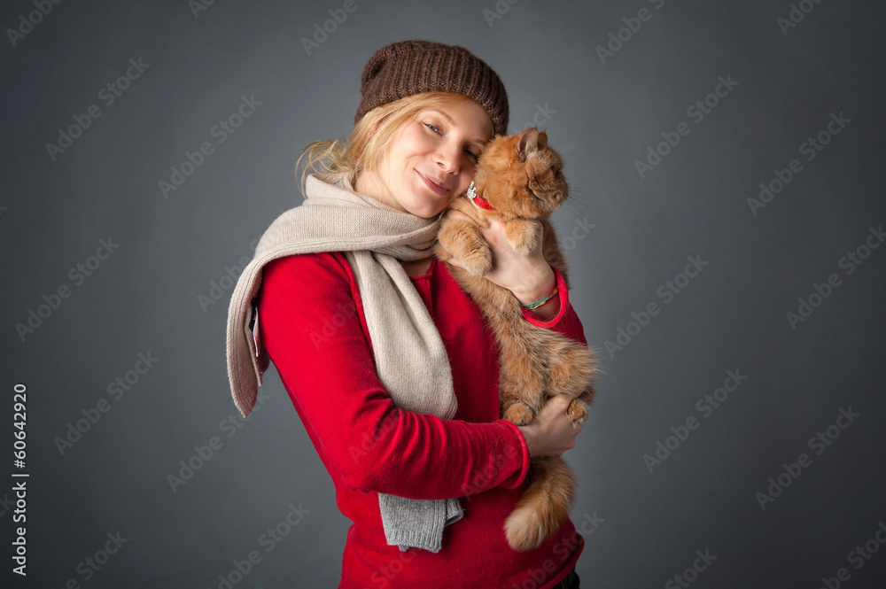 Beautiful woman hugging her red cat portrait on grey background. Beautiful woman hugging her red cat portrait on grey background.
