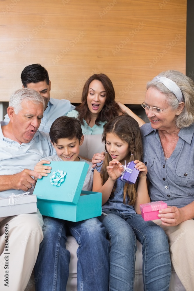 Extended family sitting on sofa with gift boxes in living room