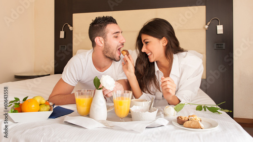 Young happy couple having breakfast in luxury hotel room. photo