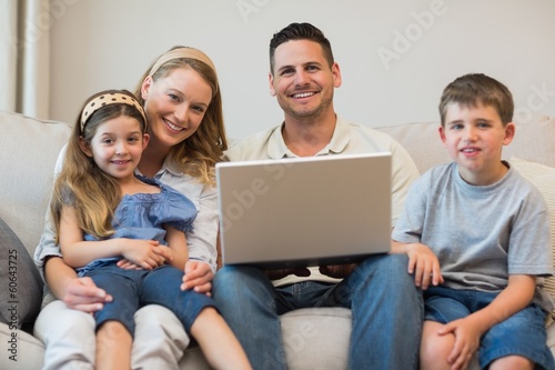 Happy family with laptop on sofa