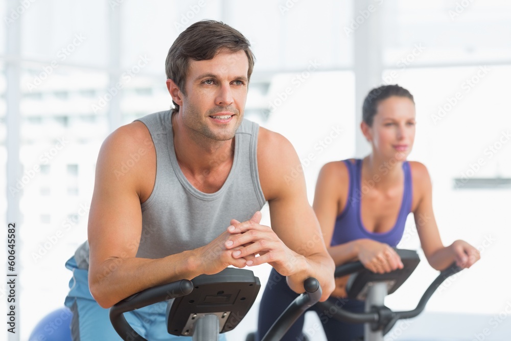 Smiling couple working out at spinning class Smiling couple working out at spinning class